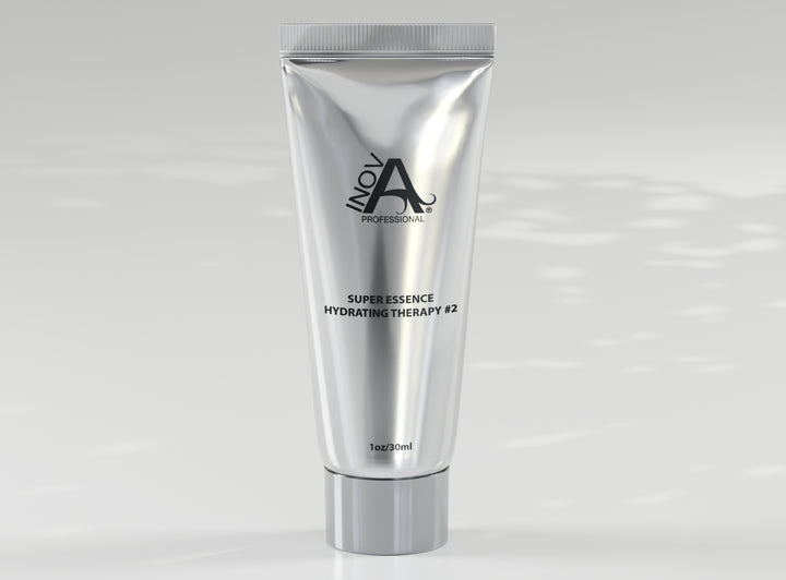 Close-up of Inova Professional Super Essence Hydrating Therapy #2 in a sleek metallic silver squeeze tube with black text and logo, standing upright on a reflective white surface. The tube is labeled 1oz/30ml, highlighting a premium hair care treatment